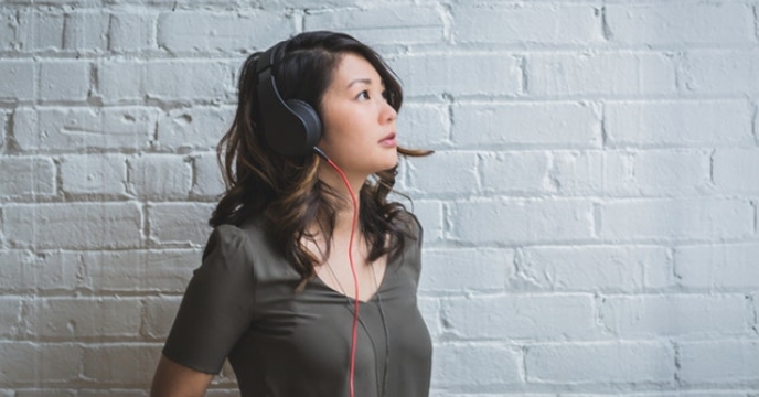 Woman in grey listening to music with headphones
